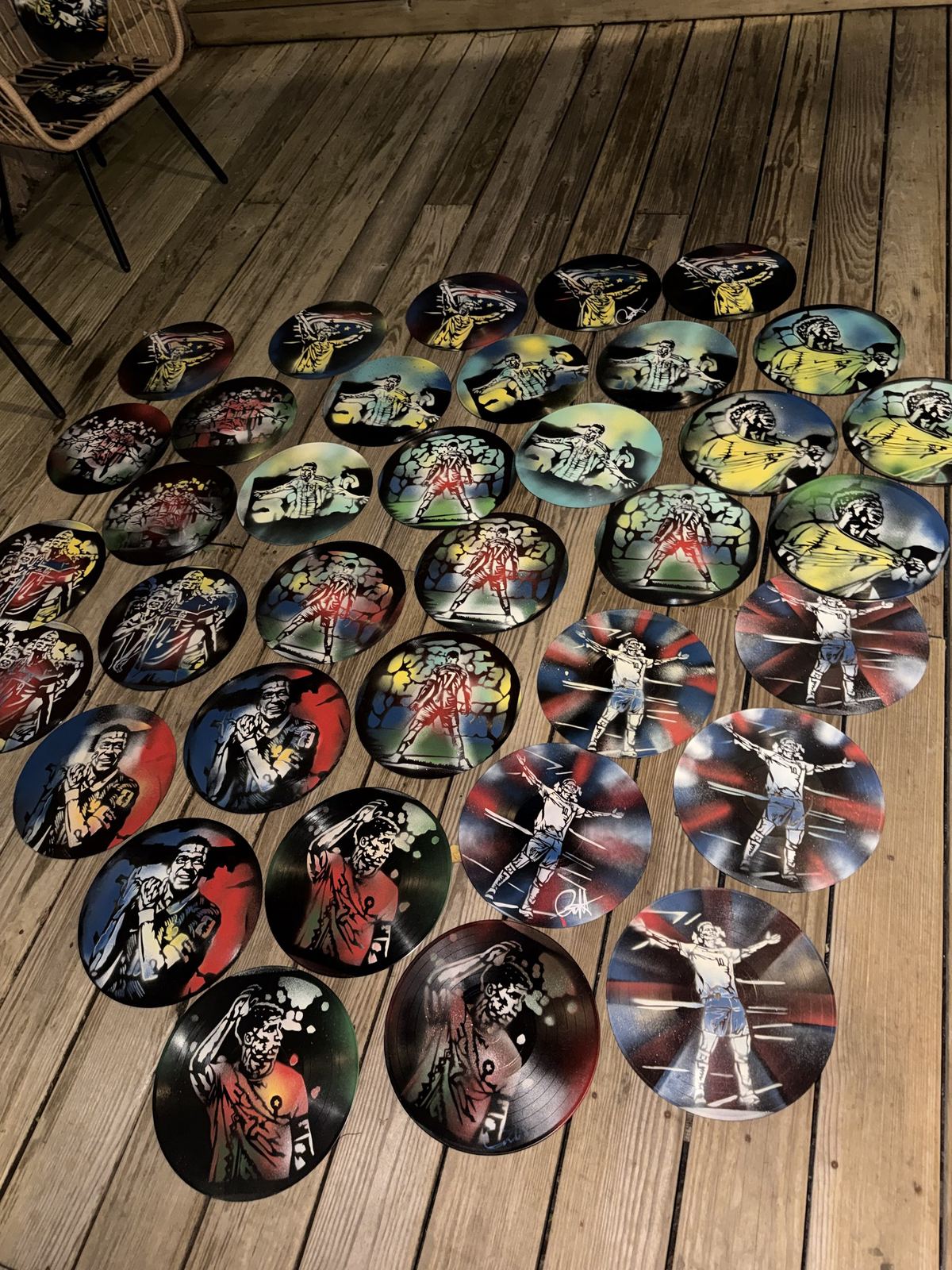 Dozens of painted records laid out on a wooden deck before a drop