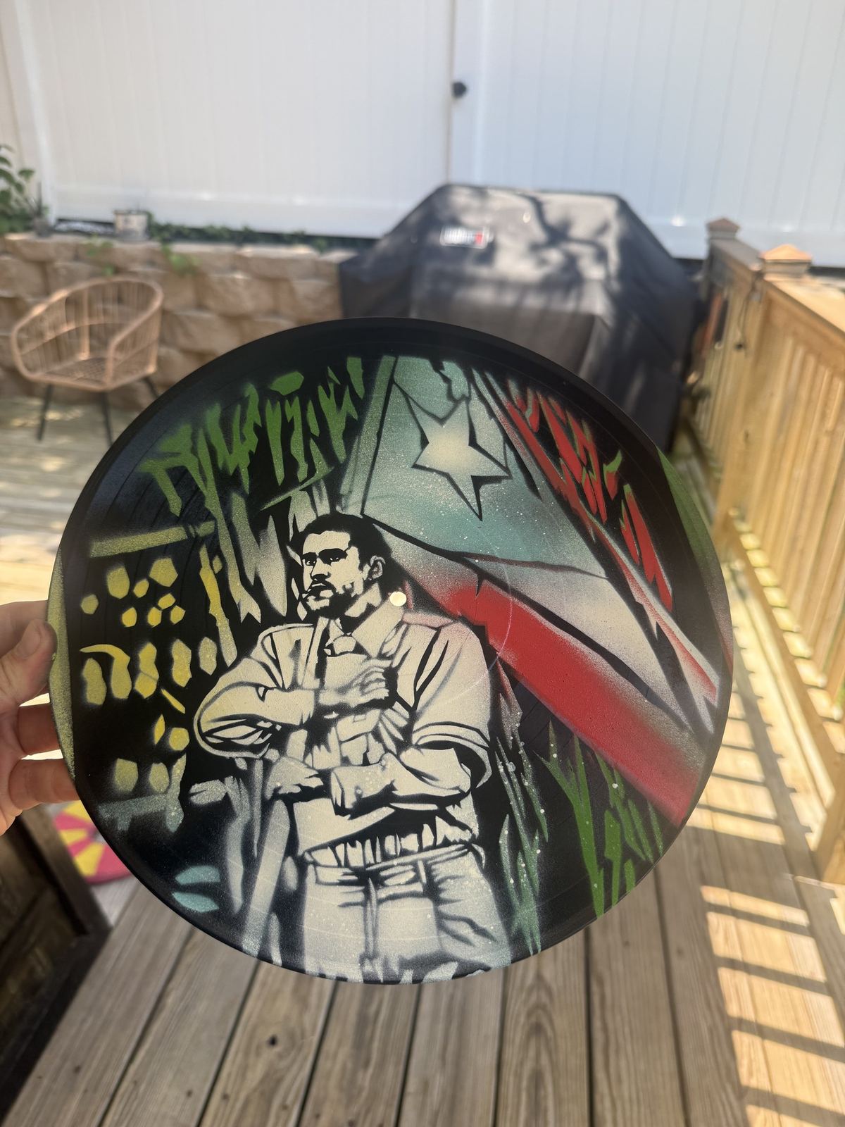 Stencil of a man in front of a red, white and blue flag on a vinyl record by Andres Gallardo