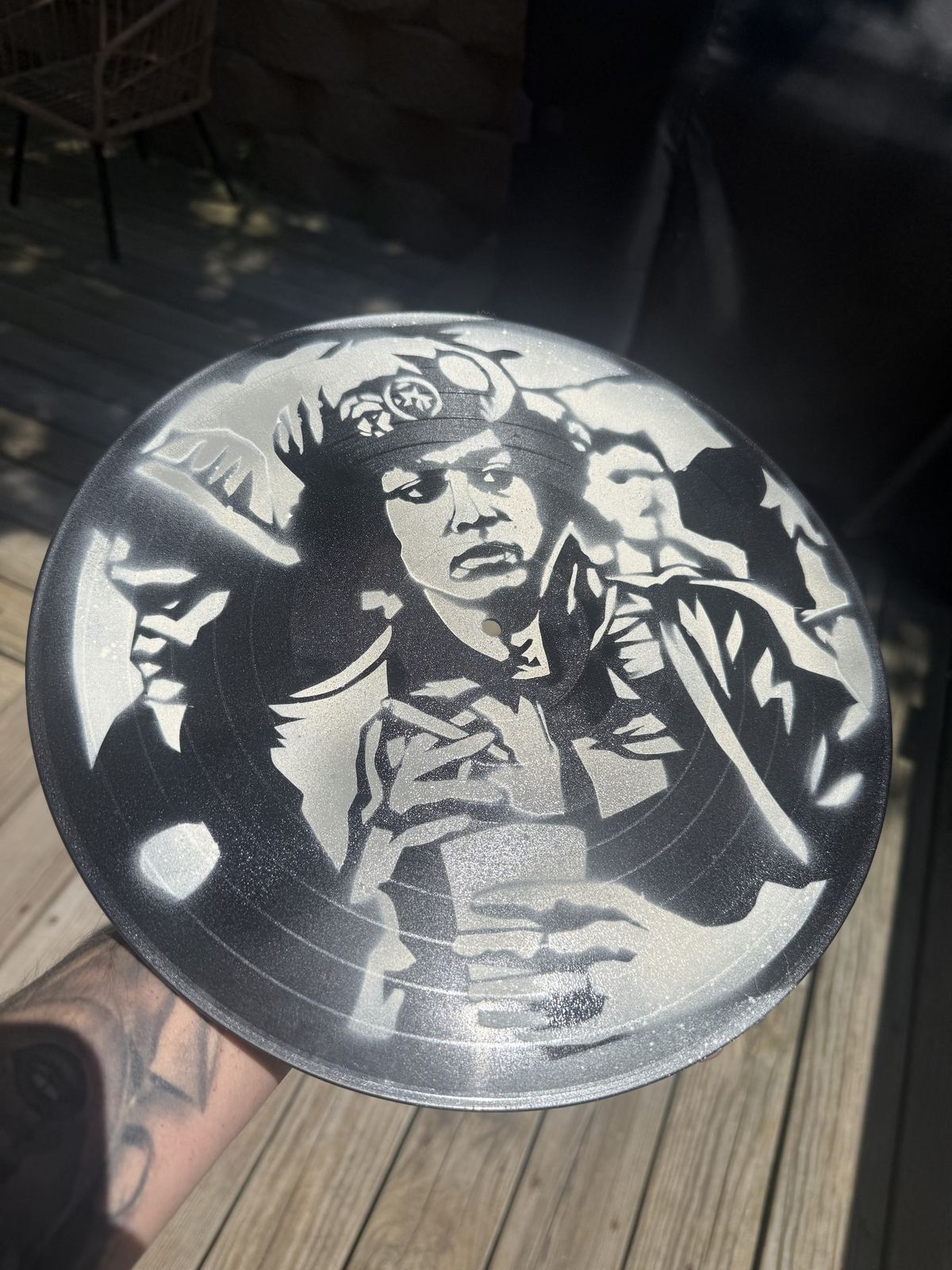 Stencil portrait of a woman on a vinyl record, held up by Andres Gallardo
