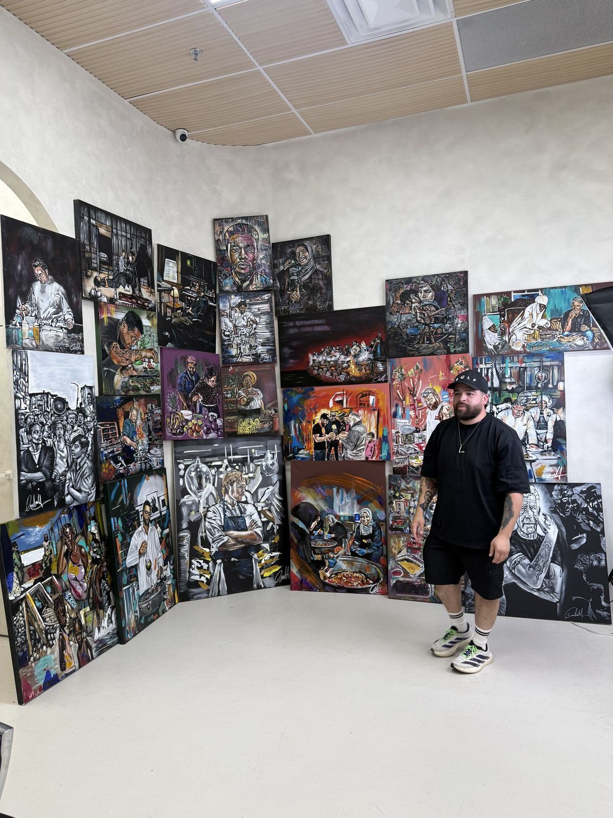 Andres Gallardo standing among his canvases in a gallery room