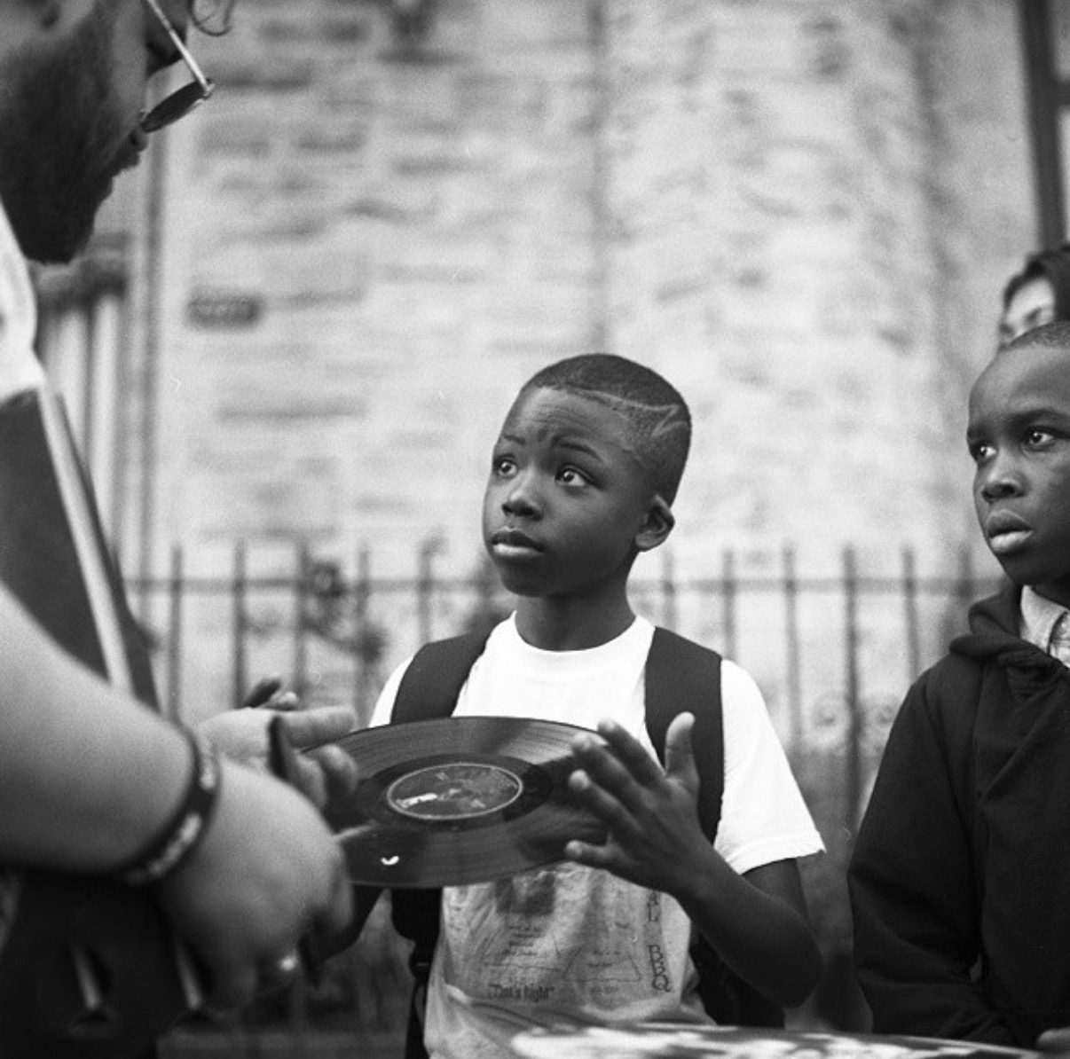 A boy in Harlem holding a hand-painted record he has just found, photo by @kingtexas