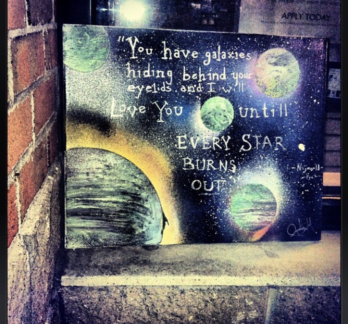 The first GEM: a small canvas of planets with the words You have galaxies hiding behind your eyelids, left against a brick wall