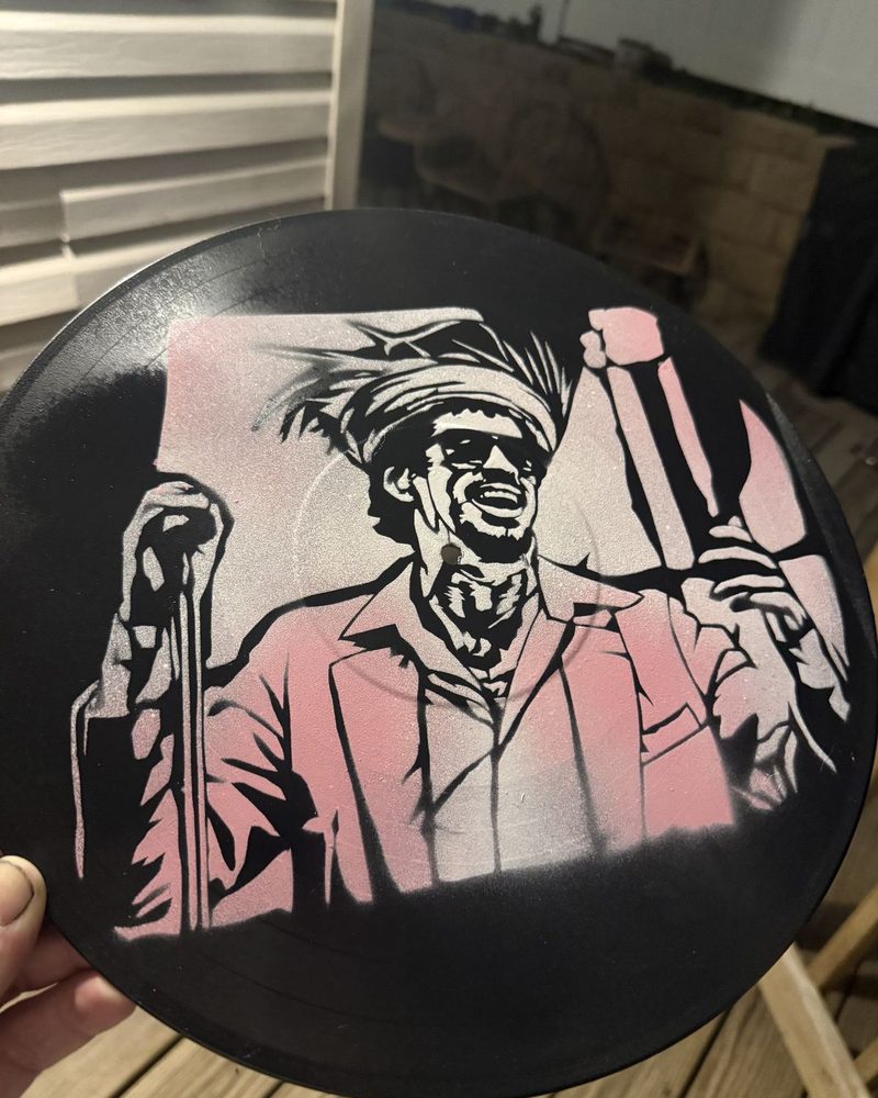 Stencil of a man in a pink shirt on a vinyl record by Andres Gallardo
