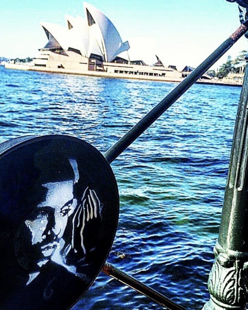 A GEM Movement record piece hung on a railing across the water from the Sydney Opera House