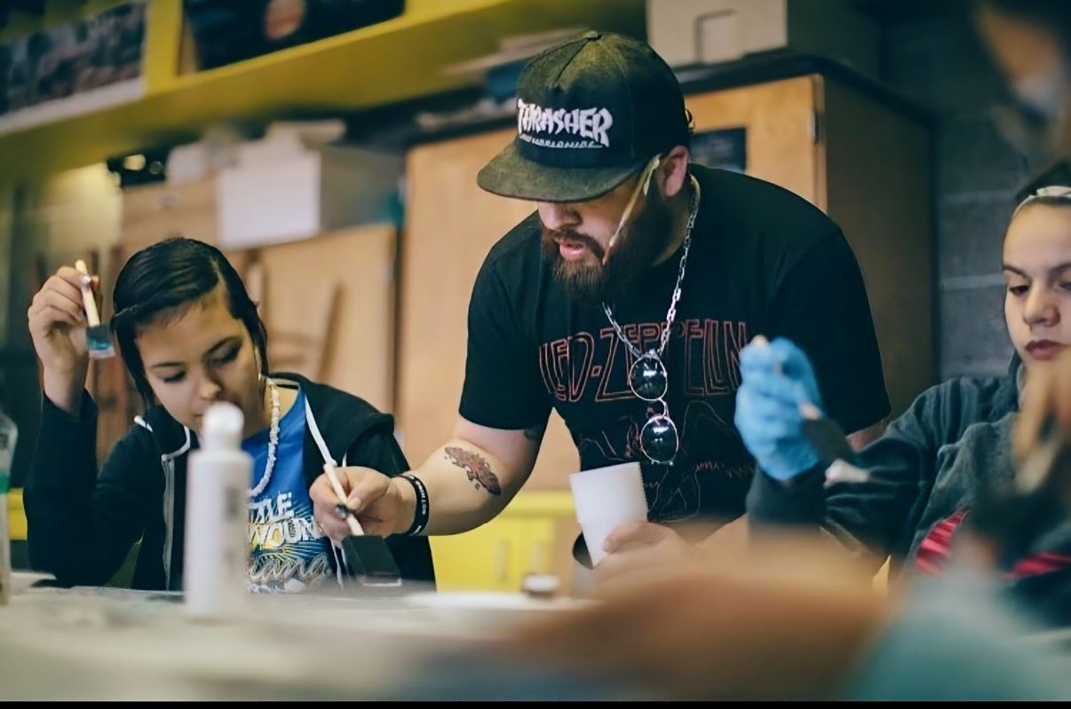 Andres Gallardo painting alongside students at Lakota Children's Enrichment in South Dakota